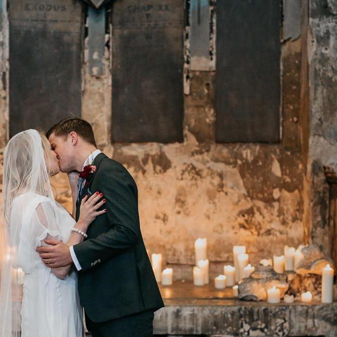 Bride and  grooms first kiss with candle light backdrop