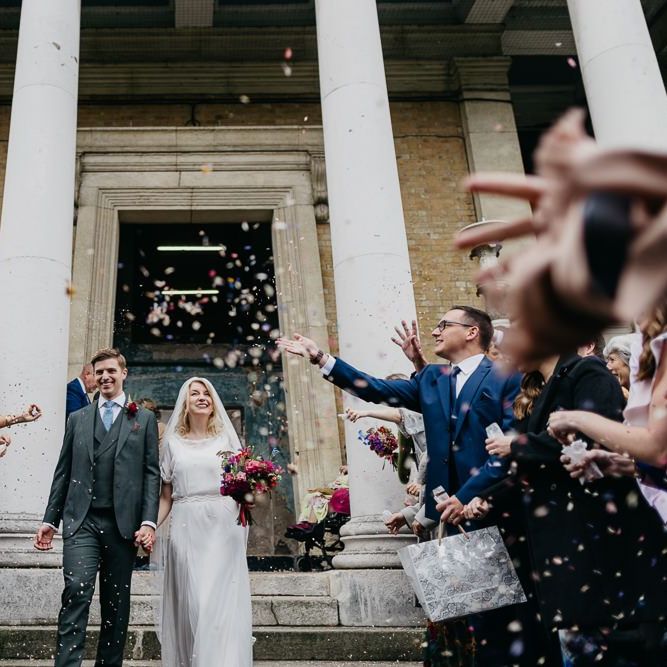 Bride and groom confetti shot as they tie the knot at city celebration in London with pine cone wedding decor