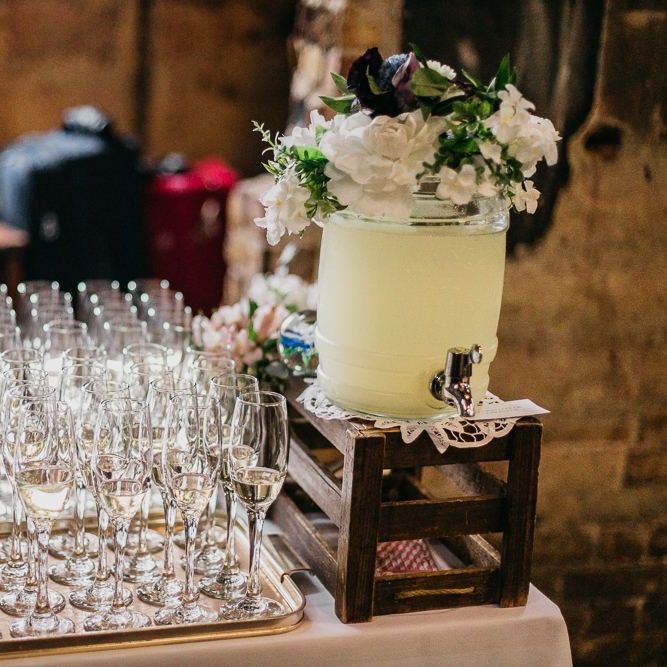 Drinks table at colourful and fun reception in London with floral and pine cone wedding decor