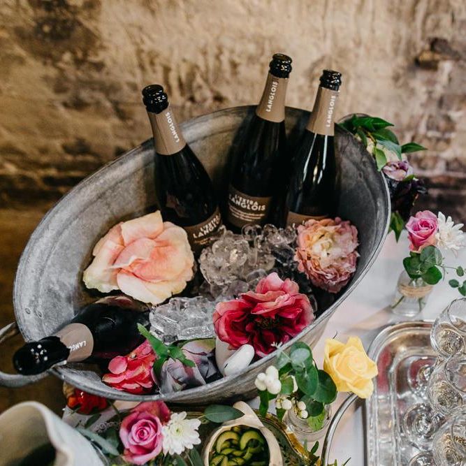 Drinks table at colourful and fun reception in London with floral and pine cone wedding decor