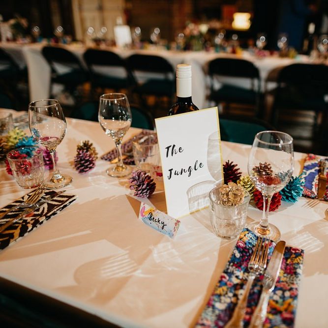 Reception styling for colourful, fun and eclectic day with pine cone wedding decor and hand painted placecards