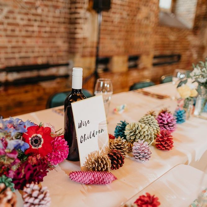 Styling for colourful and eclectic day with pine cone wedding decor and bright floral centrepieces