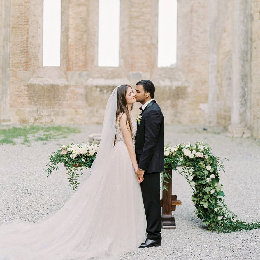 Groom in Black Tie Suit Kissing His Bride in a Rara Avis Wedding Dress