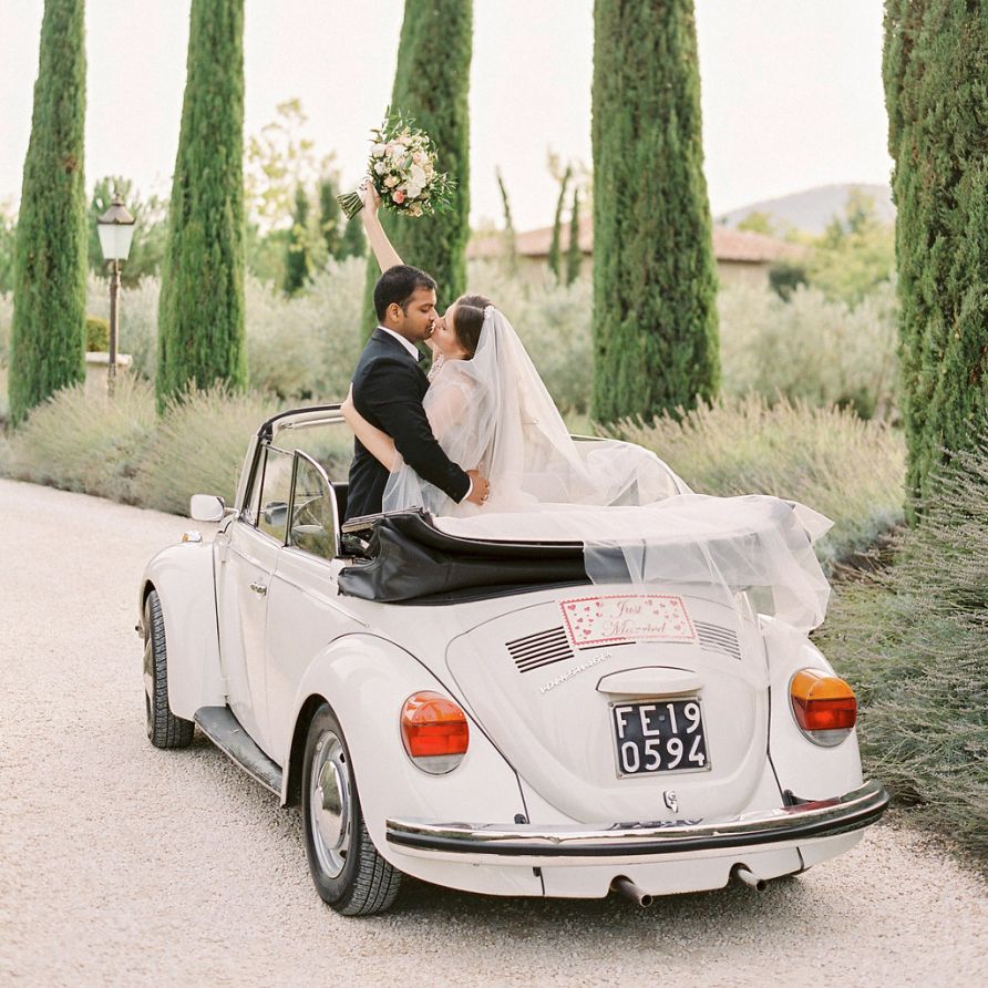 Bride in a Rara Avis Wedding Dress and Groom in Black Tuxedo in Their Convertible Beetle Wedding Car