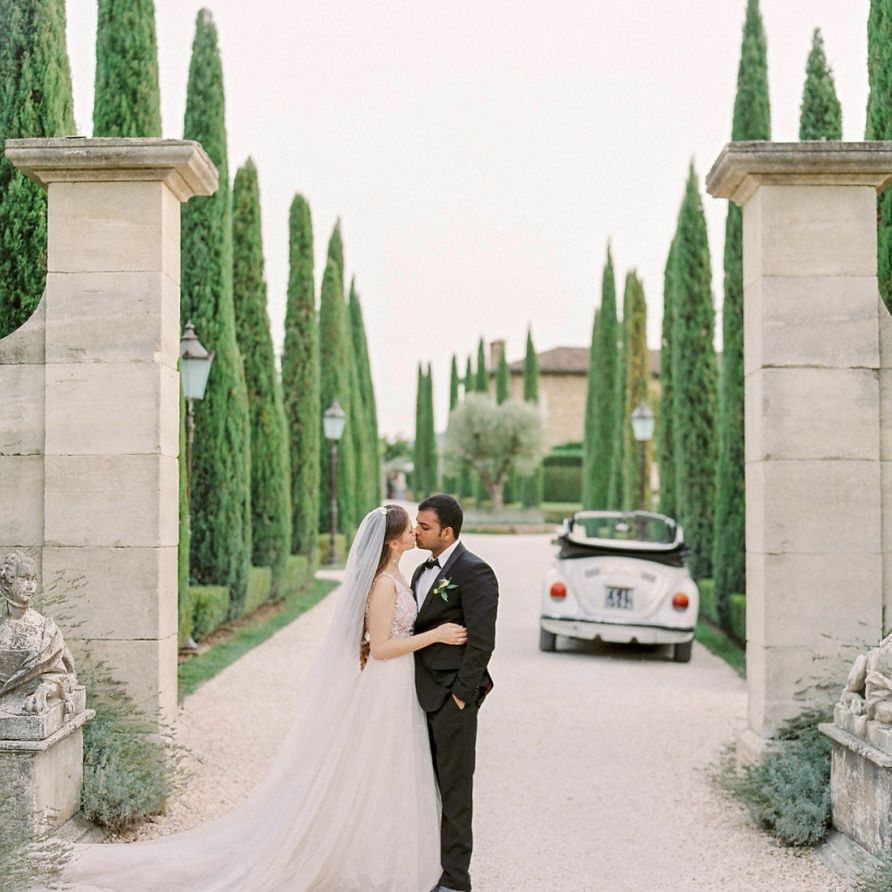 Bride in a Rara Avis Wedding Dress and Groom in Black Tuxedo Kissing with the Tuscan Countryside as their Backdrop