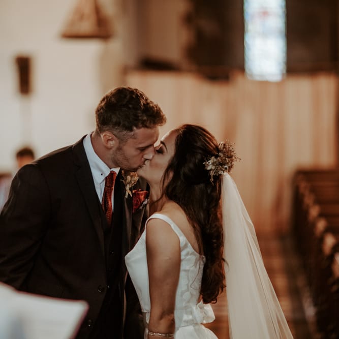 Bride and groom kissing at socially distanced church wedding ceremony