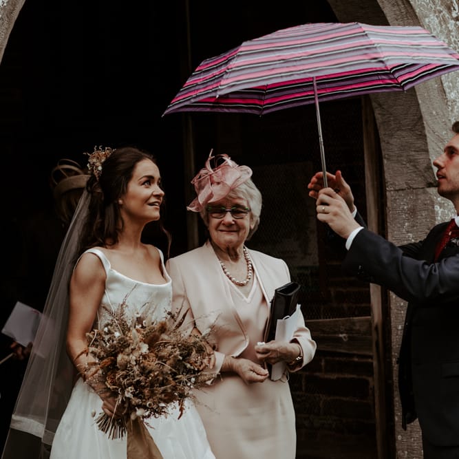 Groom sheltering his bride with an umbrella