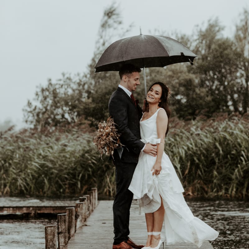 Bride and groom standing under an umbrella at September 2020 Wedding