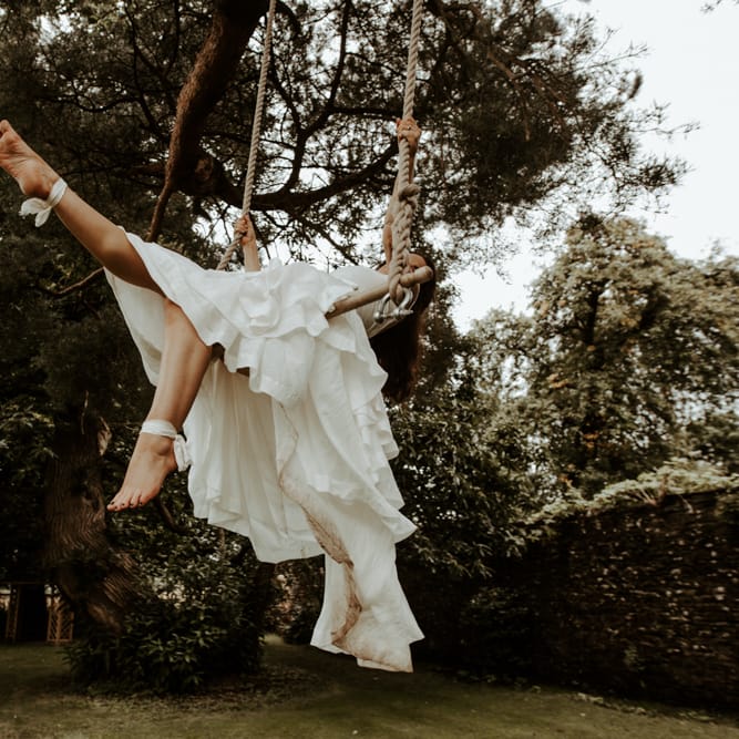 Bride swinging on a trapeze in layered skirt wedding dress