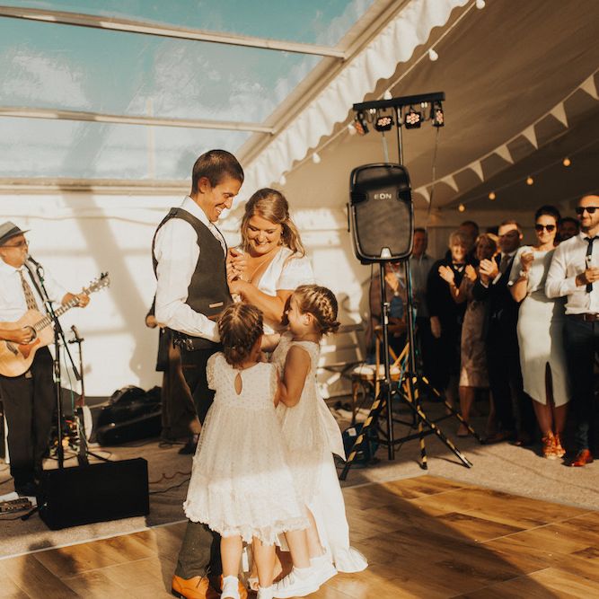 Bride in Eliza Jane Howell wedding dress and groom with their daughters dancing