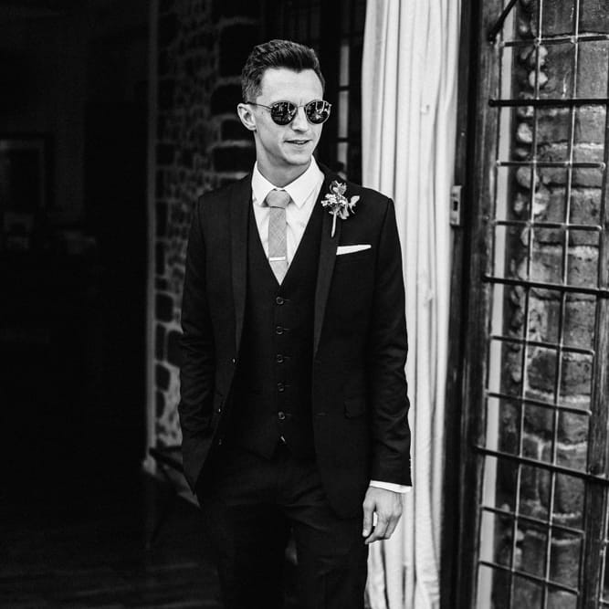 Groom in Black Three Piece Suit with Grey Tie and Personalised Tie Clip | Ivania Pronovias Wedding Dress with Long Sleeves and Minimalist Styling | Chris Barber Photography