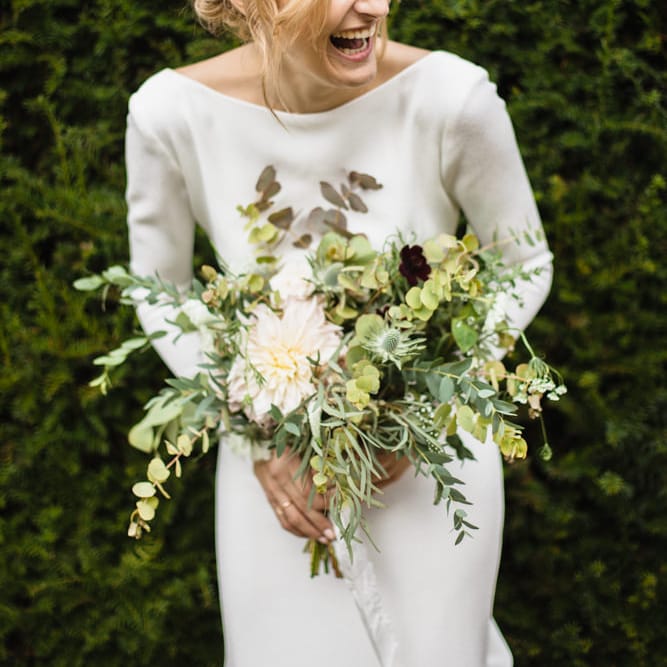 Bride in Long Sleeved Wedding Dress with Plunging V Back and Cuff Buttons by Pronovias | Bridal Bouquet of Scabious, Ammi Majus, Veronica, Snowberries, Chocolate Cosmos, Black Scabious, Cafe au Lait Dahlias and Majolica Spray Roses with White Trailing Ribbon | Bridal Up Do | Ivania Pronovias Wedding Dress with Long Sleeves and Minimalist Styling | Chris Barber Photography