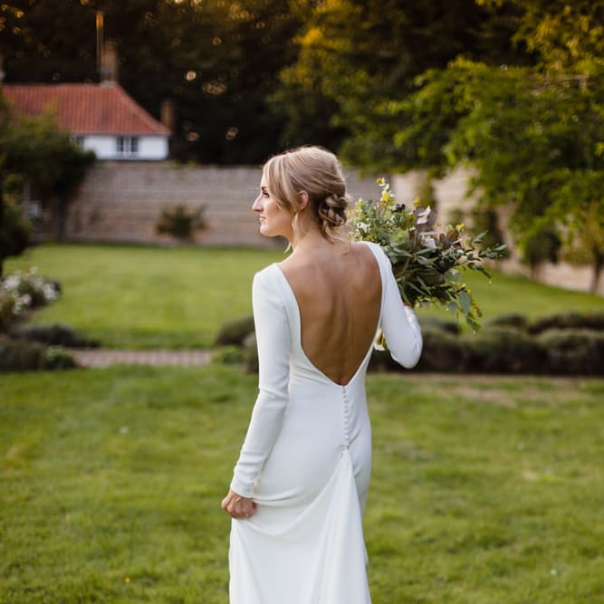 Bride in Long Sleeved Wedding Dress with Plunging V Back and Cuff Buttons by Pronovias | Bridal Bouquet of Scabious, Ammi Majus, Veronica, Snowberries, Chocolate Cosmos, Black Scabious, Cafe au Lait Dahlias and Majolica Spray Roses with White Trailing Ribbon | Bridal Up Do | Ivania Pronovias Wedding Dress with Long Sleeves and Minimalist Styling | Chris Barber Photography