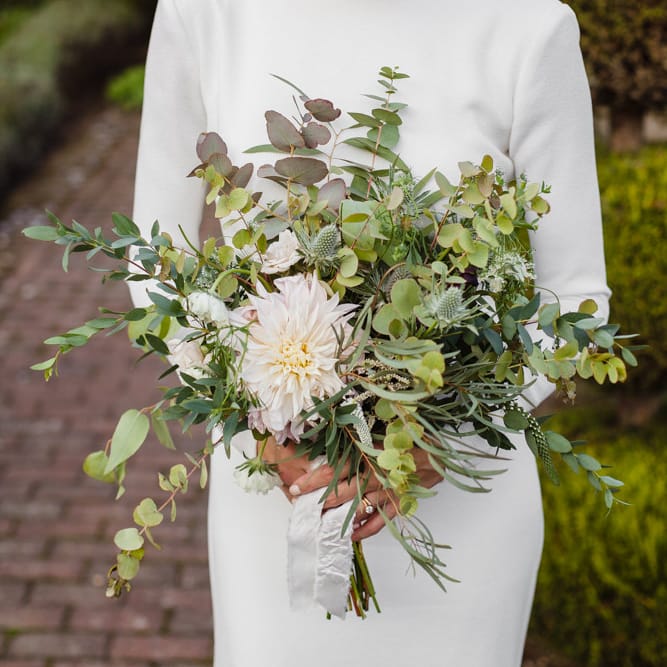 Bridal Bouquet of Scabious, Ammi Majus, Veronica, Snowberries, Chocolate Cosmos, Black Scabious, Cafe au Lait Dahlias and Majolica Spray Roses with White Trailing Ribbon | Bride in Long Sleeved Wedding Dress with Plunging V Back and Cuff Buttons by Pronovias | Ivania Pronovias Wedding Dress with Long Sleeves and Minimalist Styling | Chris Barber Photography