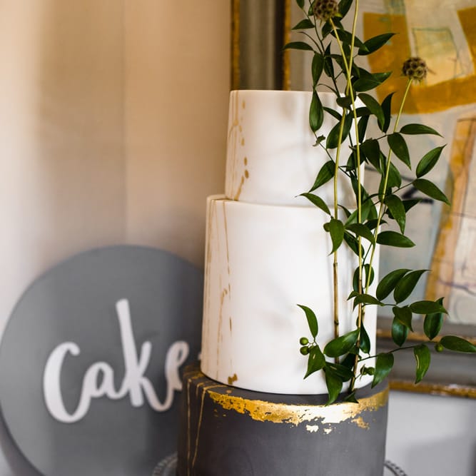 Three Tier Wedding Cake with White and Grey Icing, Gold Leaf Detail and Grey Ribbon | Ivania Pronovias Wedding Dress with Long Sleeves and Minimalist Styling | Chris Barber Photography