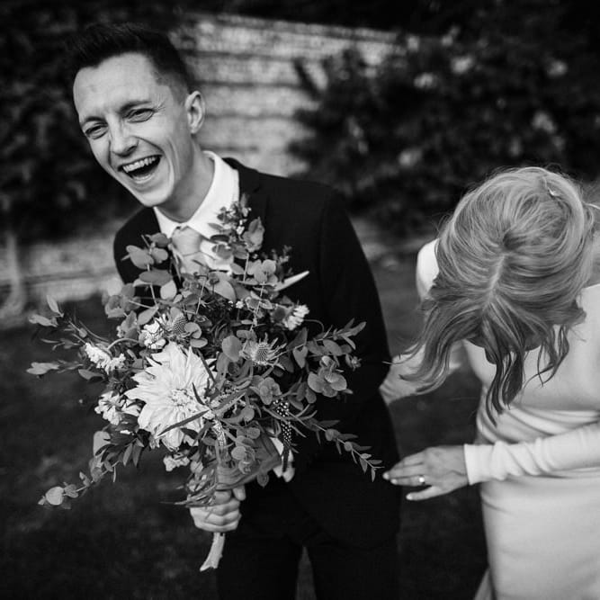 Bride in Long Sleeved Wedding Dress with Plunging V Back and Cuff Buttons by Pronovias | Groom in Black Three Piece Suit with Grey Tie and Personalised Tie Clip | Bridal Bouquet of Scabious, Ammi Majus, Veronica, Snowberries, Chocolate Cosmos, Black Scabious, Cafe au Lait Dahlias and Majolica Spray Roses with White Trailing Ribbon | Bridal Up Do | Ivania Pronovias Wedding Dress with Long Sleeves and Minimalist Styling | Chris Barber Photography