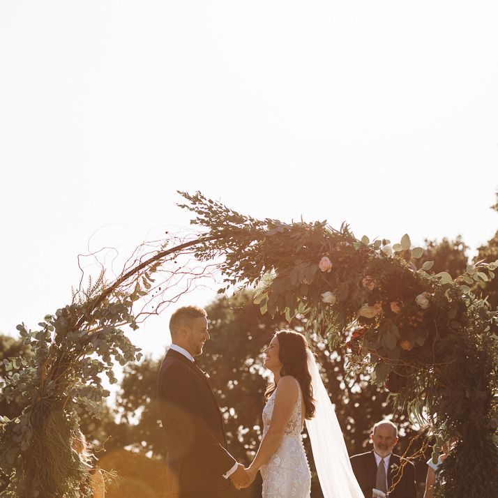 Beautiful floral and foliage hoop decor at intimate outdoor ceremony