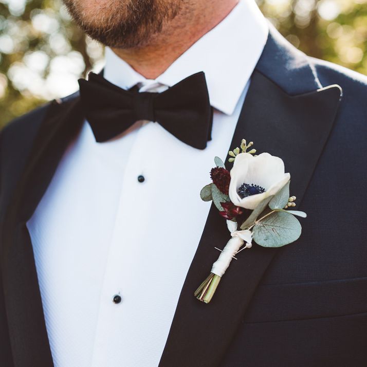 Groom wearing floral buttonhole and bow tie at Crouchers Orchards for outdoor wedding ceremony