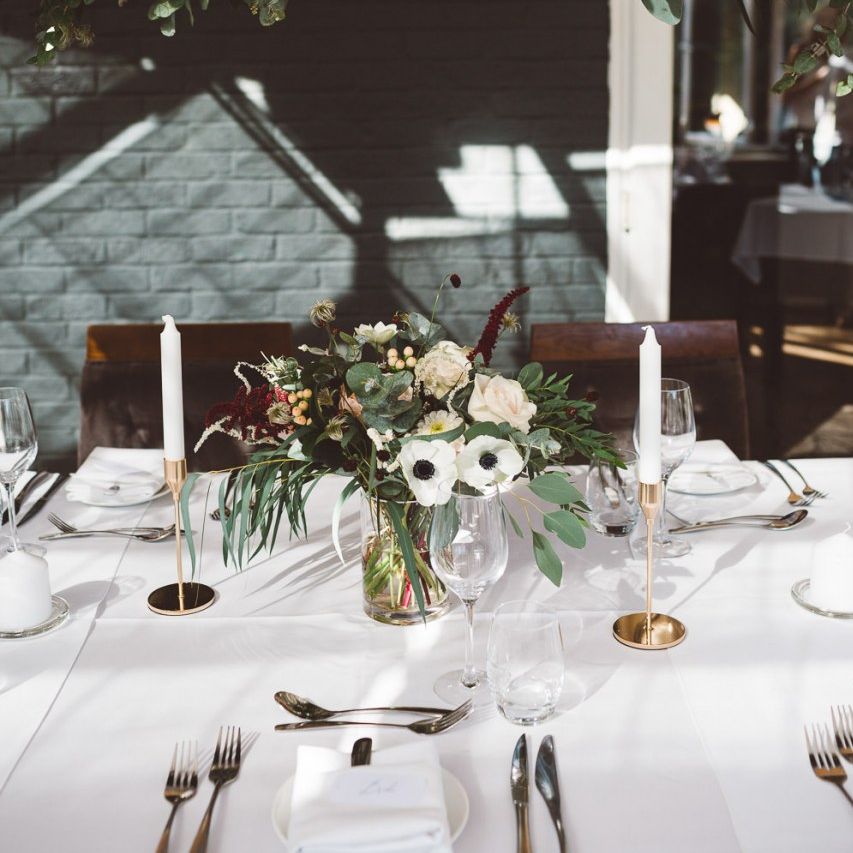 Hanging foliage and floral table arrangements styled with gold candlesticks for intimate dinner