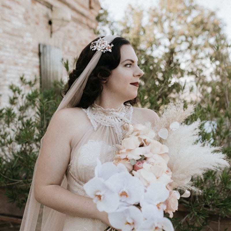 Bride in homemade wedding dress holds  beautiful orchid bouquet with pampas grass
