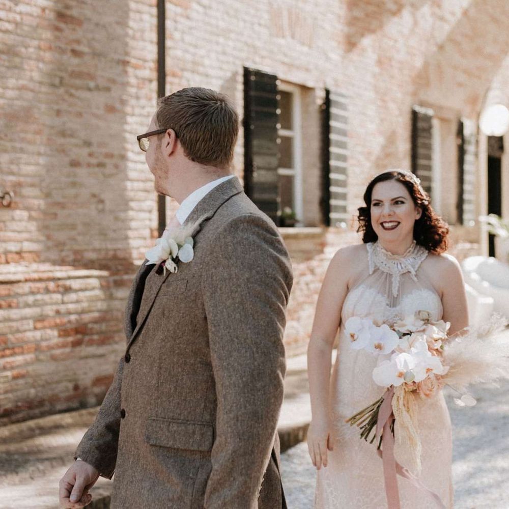 Groom turns to see bride holding orchid bouquet at first look