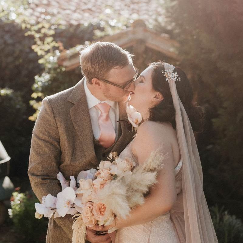 Bride holding orchid bouquet kisses groom at Italian wedding