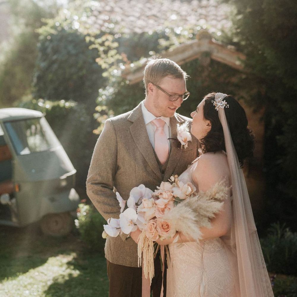 Bride holding orchid bouquet with groom at Italian wedding venue