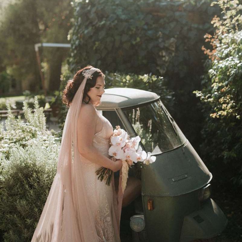 Bride in handmade wedding dress with blush orchid bouquet