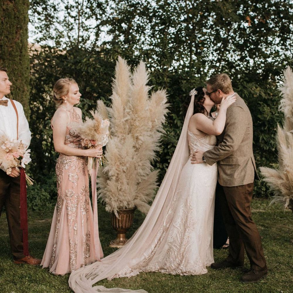 Bride and groom kiss at outdoor ceremony with pampas grass decor
