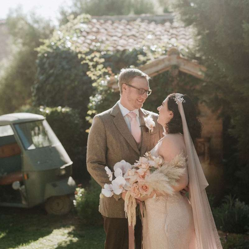Bride holds orchid bouquet as she looks at groom