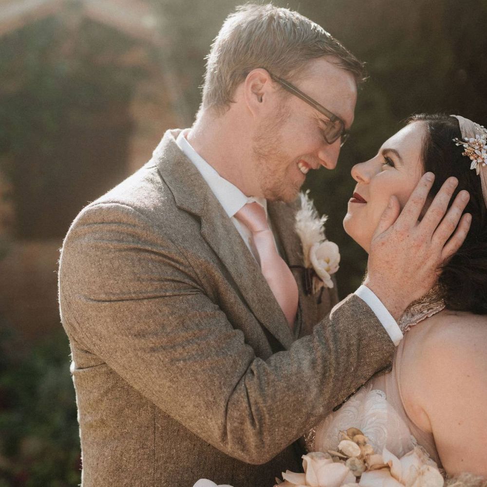 Bride holds orchid bouquet as she looks at groom