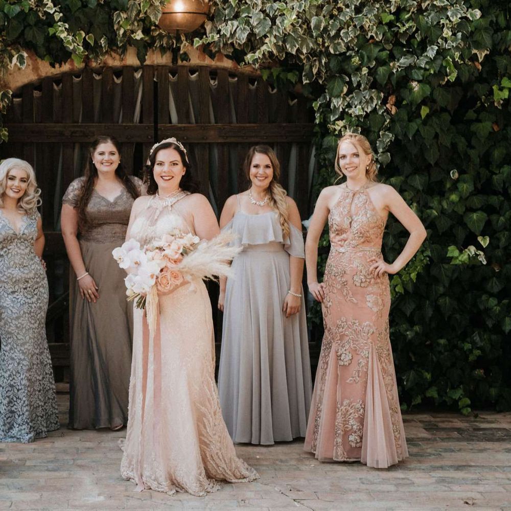 Mismatched bridesmaid dresses with bride in homemade wedding dress holding orchid bouquet