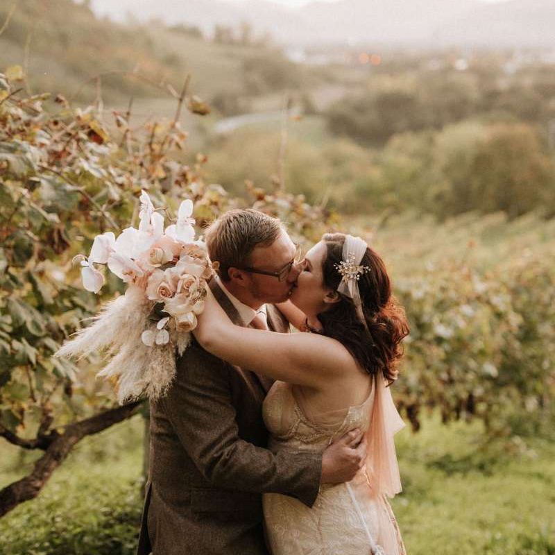 Bride holding orchid bouquet kisses groom