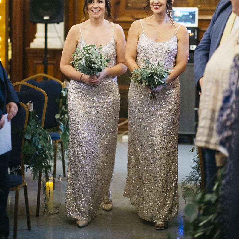 Bridesmaids wearing beautiful embellished dresses and clutching simple white foliage bouquets