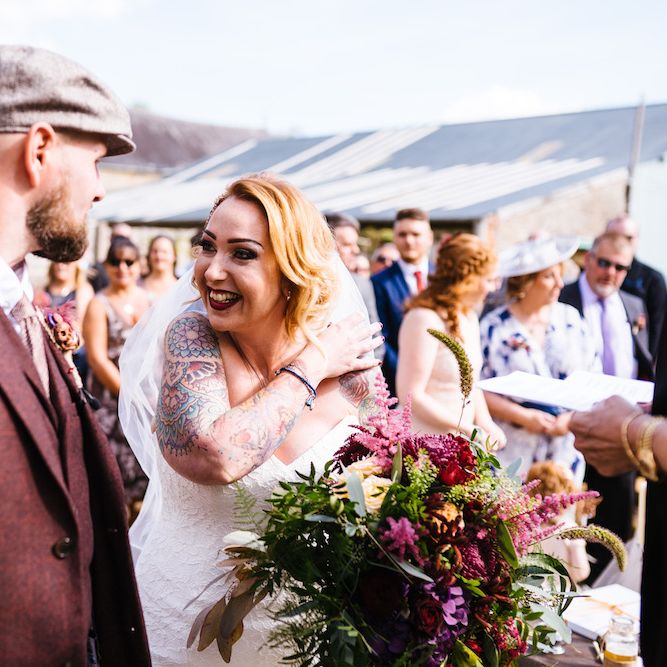Wedding Ceremony | Bride in Strapless Sassi Holford Wedding Dress with Sweetheart Neckline | Groom in Burgundy Tweed Three Piece Suit | Bright Bouquet | Edison Bulb Floral Installation at Kingsthorpe Lodge Barn Wedding | Johnny Dent Photography