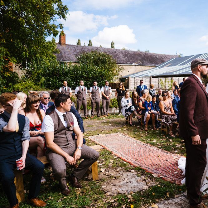 Wedding Ceremony | Bride in Strapless Sassi Holford Wedding Dress with Sweetheart Neckline | Groom in Burgundy Tweed Three Piece Suit | Edison Bulb Floral Installation at Kingsthorpe Lodge Barn Wedding | Johnny Dent Photography