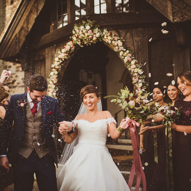 Church Confetti Moment | Bride in Lillian West Bridal Separates | Groom in Navy Suit &amp; Tweed Waistcoat | Burgundy &amp; Gold Winter Wedding at Ramster Hall Weddings, Surrey | Matt Penberthy Photography | John Harris Wedding Films