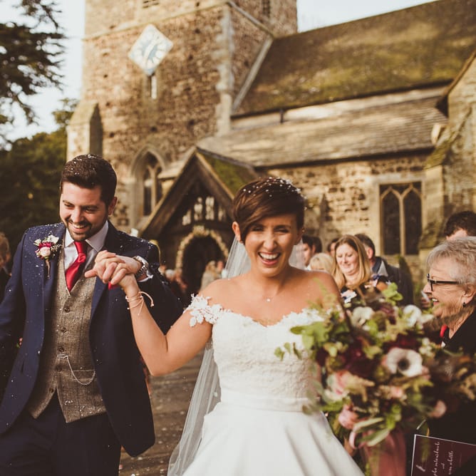 Church Confetti Moment | Bride in Lillian West Bridal Separates | Groom in Navy Suit &amp; Tweed Waistcoat | Burgundy &amp; Gold Winter Wedding at Ramster Hall Weddings, Surrey | Matt Penberthy Photography | John Harris Wedding Films