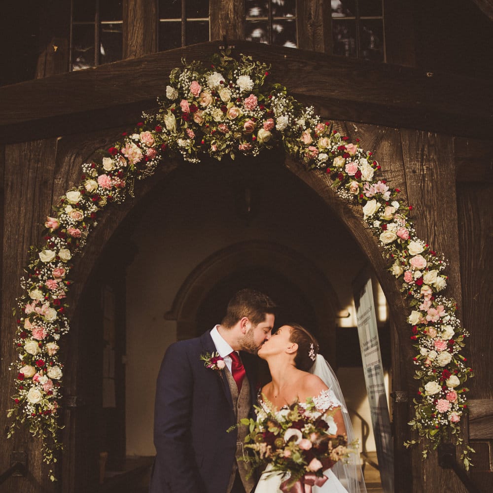 Church Floral Arch Wedding Flowers | Bride in Lillian West Bridal Separates | Groom in Navy Suit &amp; Tweed Waistcoat | Burgundy &amp; Gold Winter Wedding at Ramster Hall Weddings, Surrey | Matt Penberthy Photography | John Harris Wedding Films