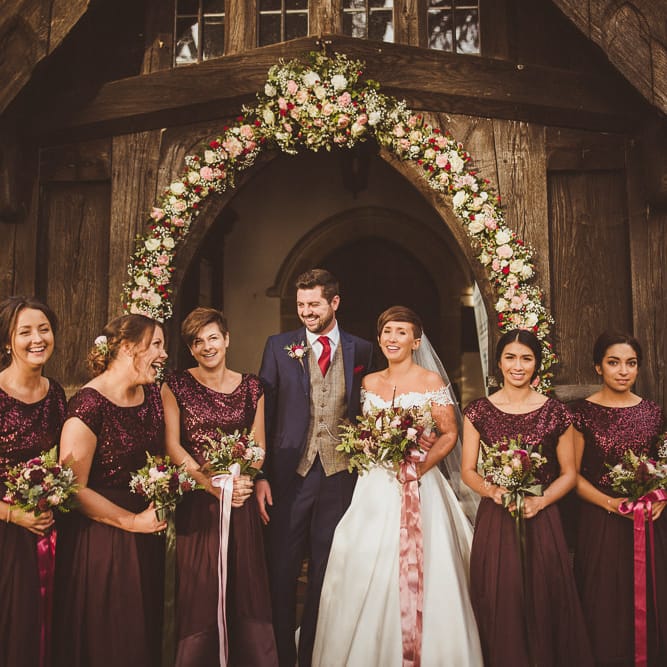 Church Floral Arch Wedding Flowers | Bride in Lillian West Bridal Separates | Bridesmaids in Burgundy Coast Sequin Top &amp; High Low Skirt Separates | Groom in Navy Suit &amp; Tweed Waistcoat | Burgundy &amp; Gold Winter Wedding at Ramster Hall Weddings, Surrey | Matt Penberthy Photography | John Harris Wedding Films