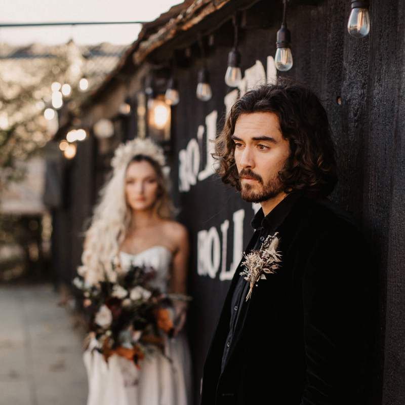 Groom in black shirt and velvet jacket for Halloween wedding