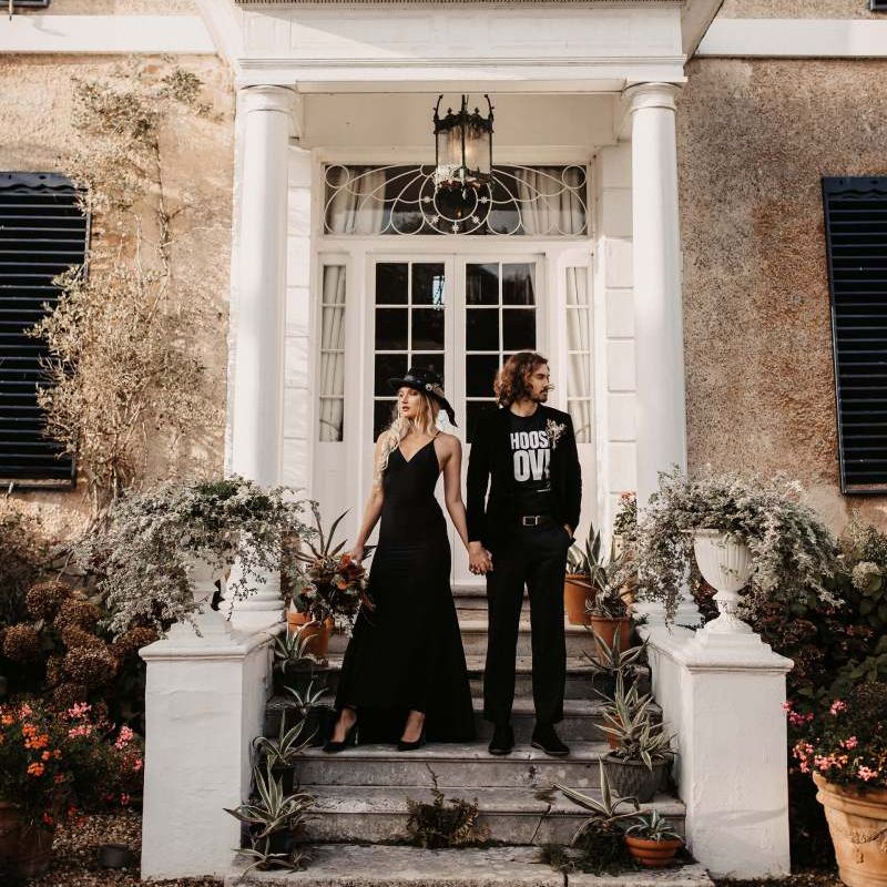 Stylish bride and groom in black wedding dress and t-shirt outside Preston Court