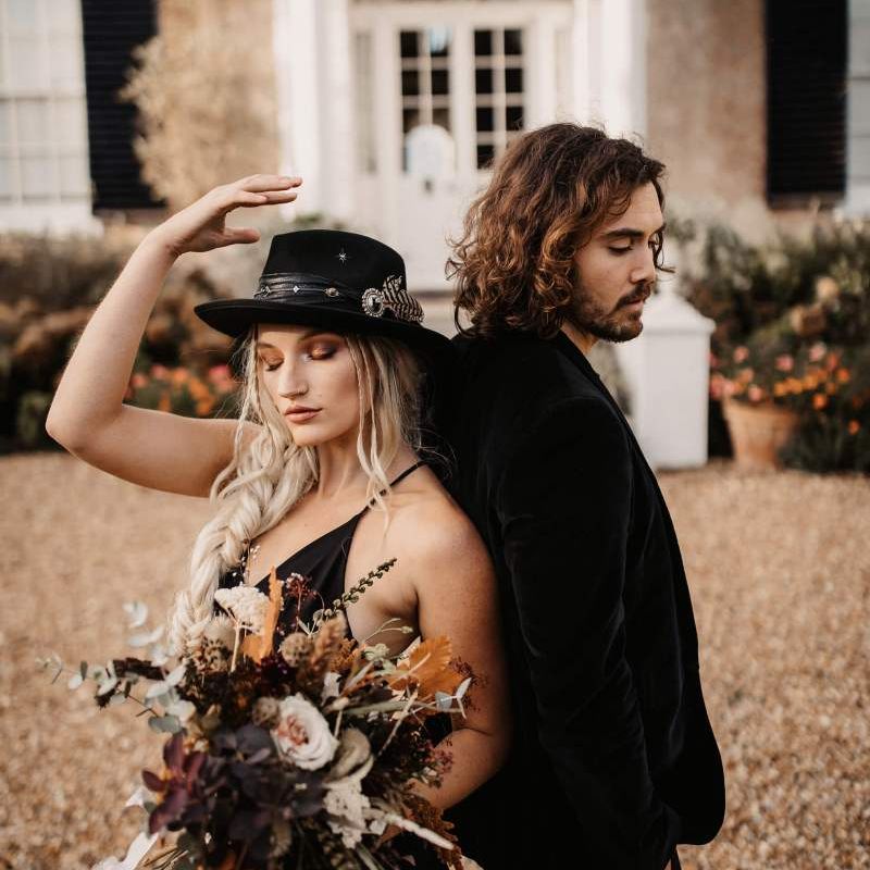 Halloween wedding with bride in black dress and hat and groom in  velvet jacket