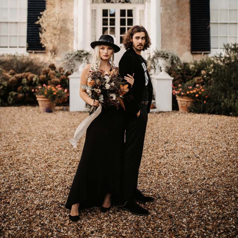 Stylish bride and groom in black wedding dress and hat for Halloween wedding  shoot
