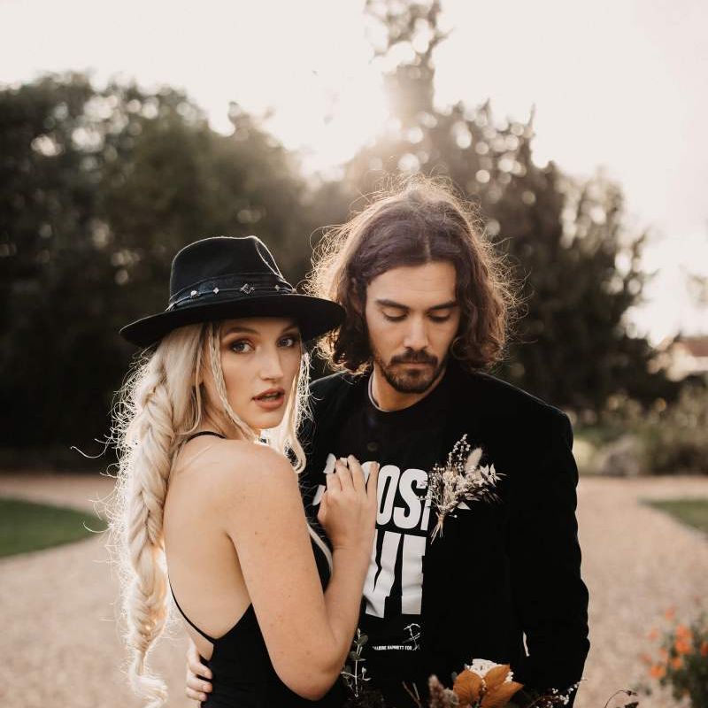 Cool bride and groom in black wedding dress, hat T-shirt and blazer for Halloween wedding  shoot