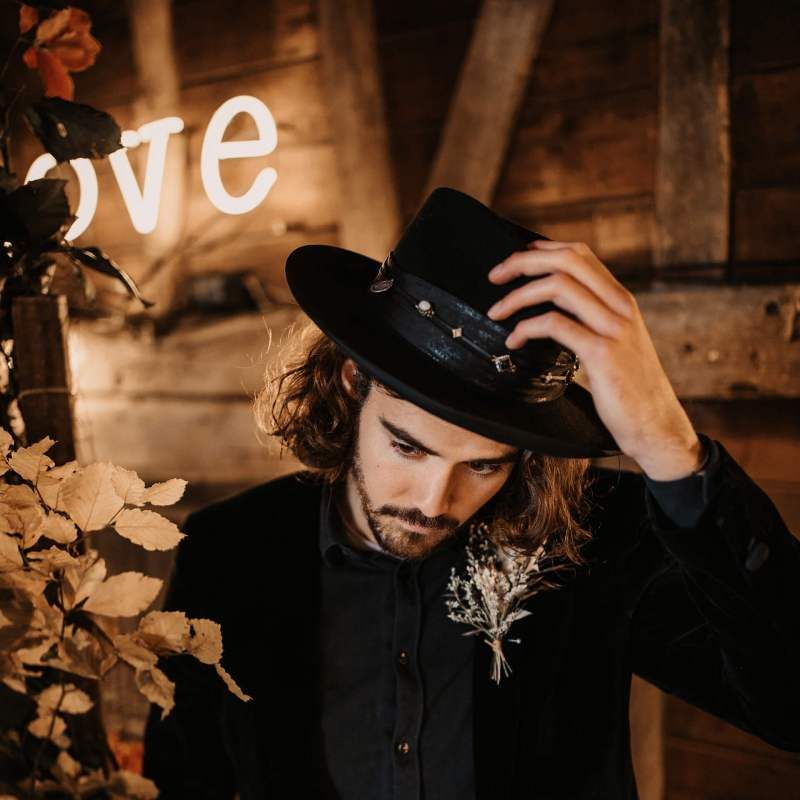 Groom in black shirt, hat and blazer at Halloween wedding