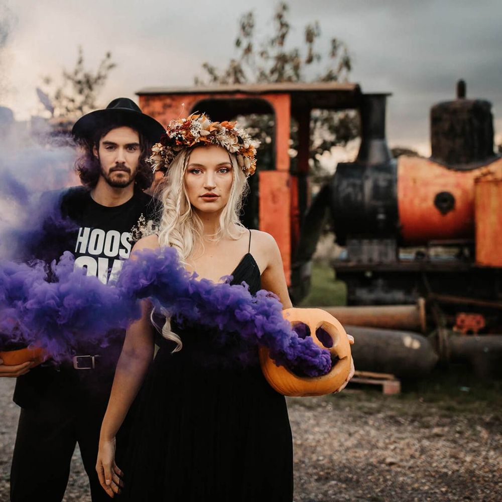 Alternative bride and groom holding smoke bombs at Halloween wedding