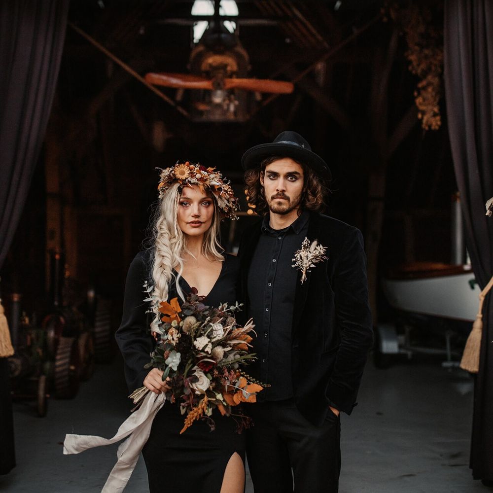 Halloween wedding inspired shoot with bride and groom in black outfits holding Autumn flowers
