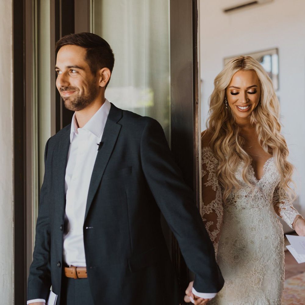 Bride and groom hold hands and read notes before their wedding ceremony