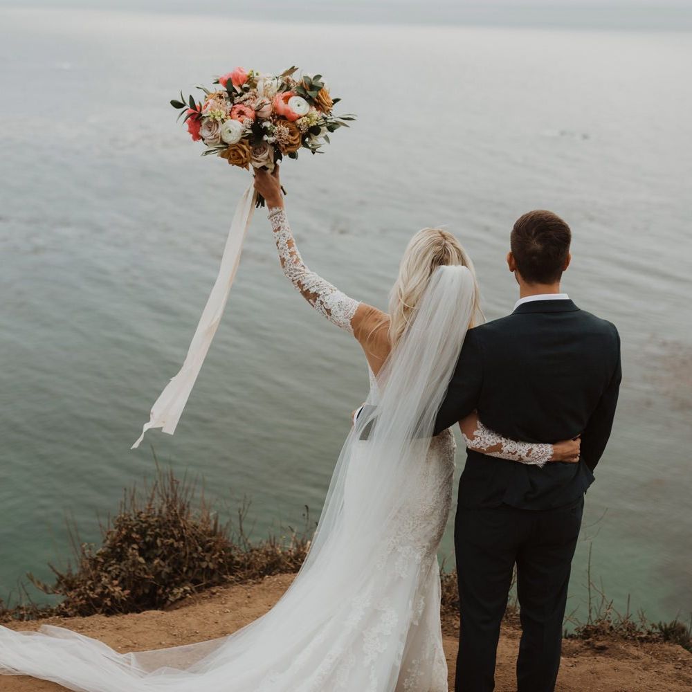 Bride holding up her coral and white wedding bouquet at California elopement